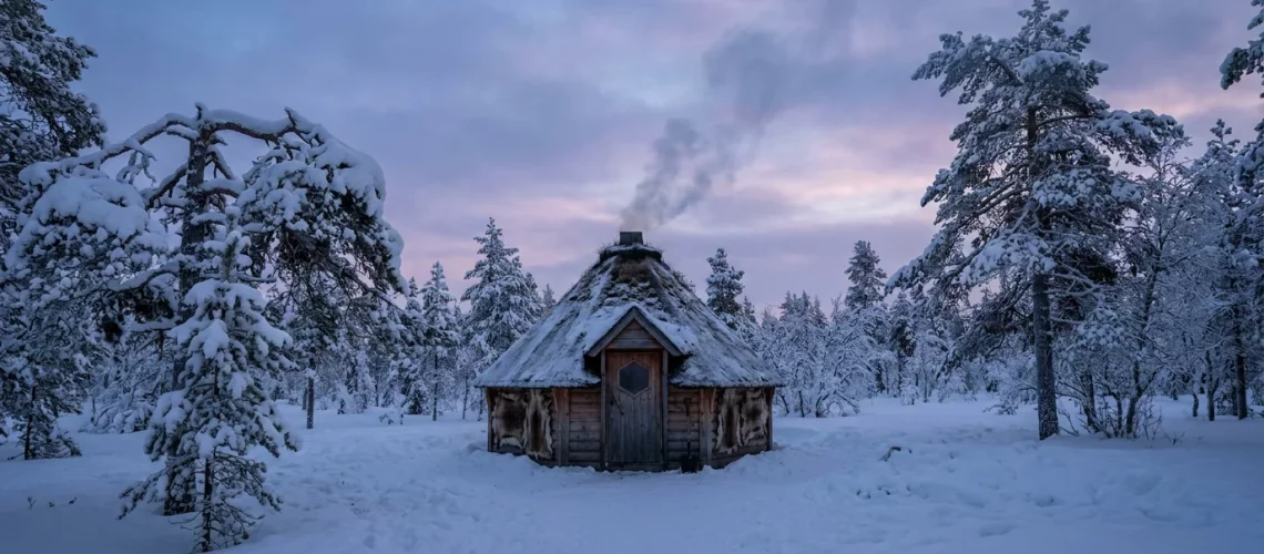 Kota finlandais traditionnel dans une clairière enneigée de Laponie au crépuscule