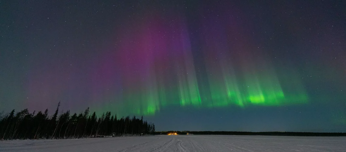 Panorama nocturne de Levi en Laponie finlandaise sous des aurores boréales vertes et violettes